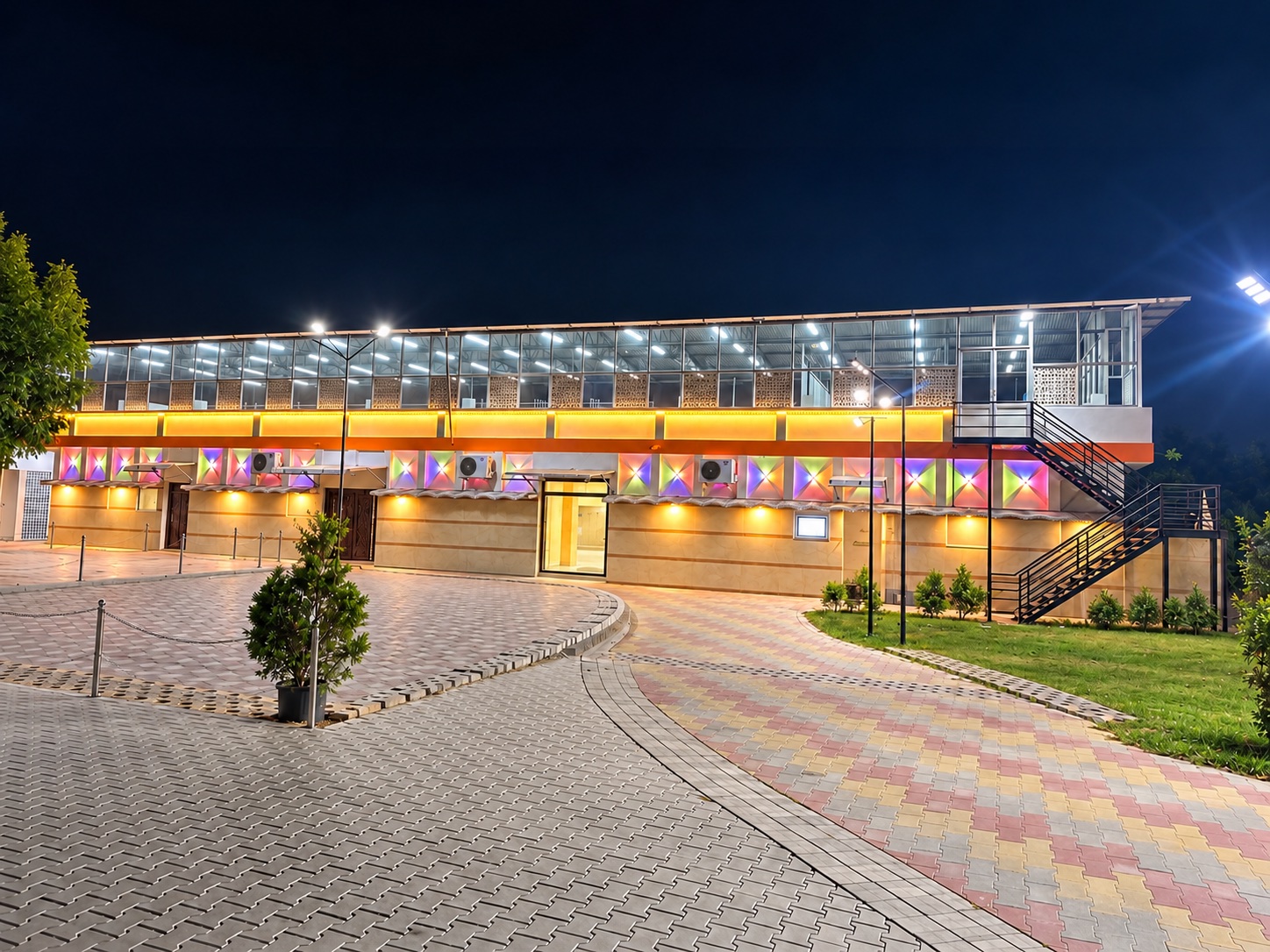 Front view of Nellimala Mini Hall and its paved parking area at night